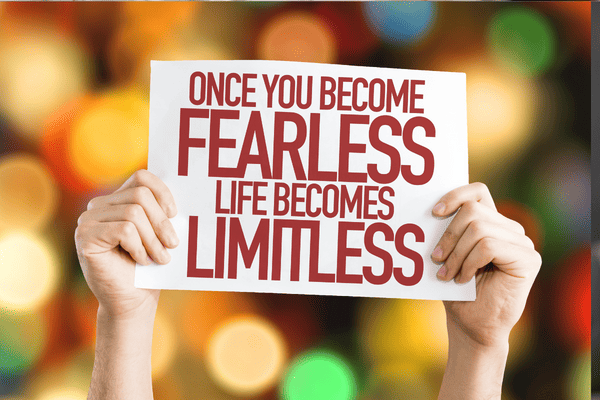 Photo of a person holding a white paper with ''once you become fearless, life becomes limitless'' written on it.