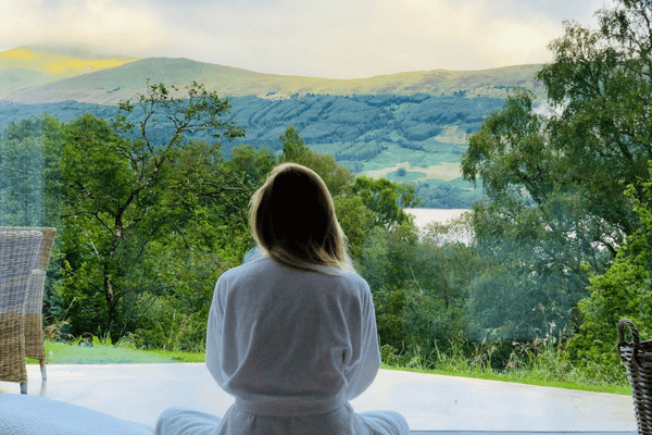 sitting woman in white robe looking at mountains during daytime