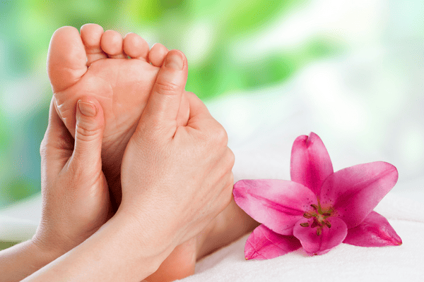 Photo of a feet being massaged with rose flower closeby.