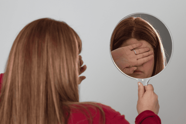 How To Feel Less Self-conscious
A lady holding out a mirror but she cannot look into the mirror.