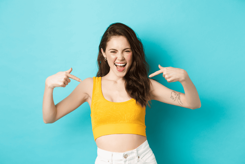 A lady on yellow top pointing at herself.