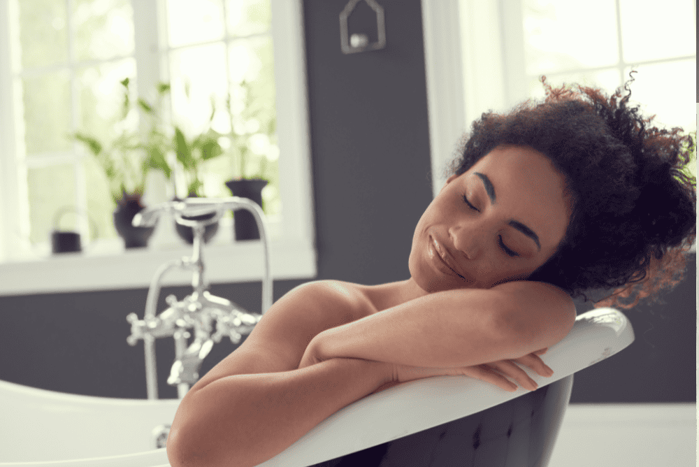 A woman in a bath tub napping.