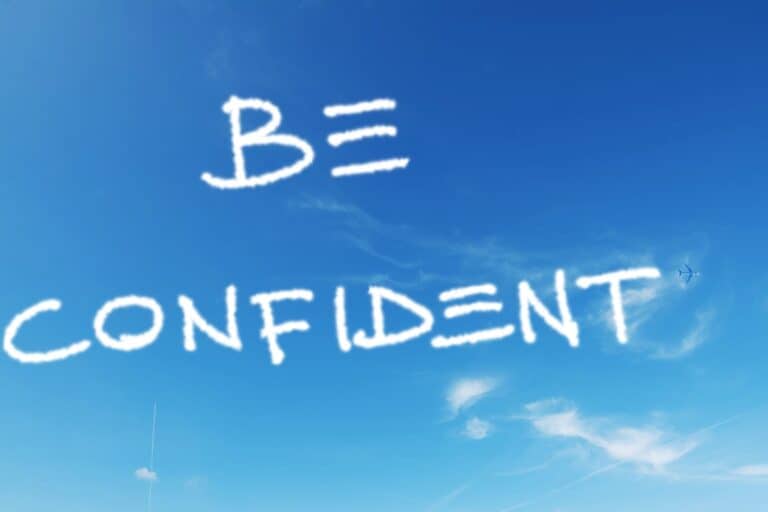 Blue sky with the words "Be Confident" gracefully written in cloud-like letters, a small airplane tracing its path in the background, illustrating how to exude confidence effortlessly.