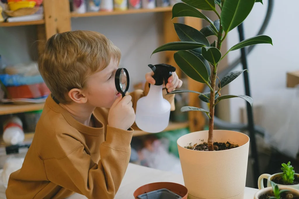 A child intently examines a potted plant with a magnifying glass, holding a spray bottle, engaging in self-care activities through the calming art of nurturing nature.