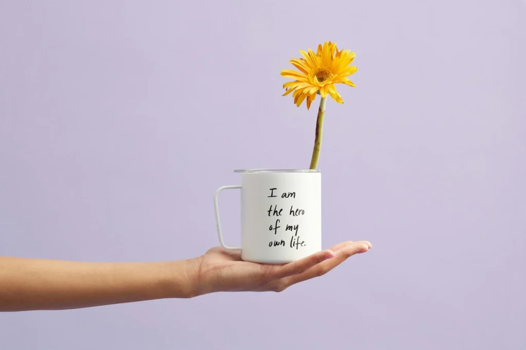 A hand holding a white mug with sunflower.