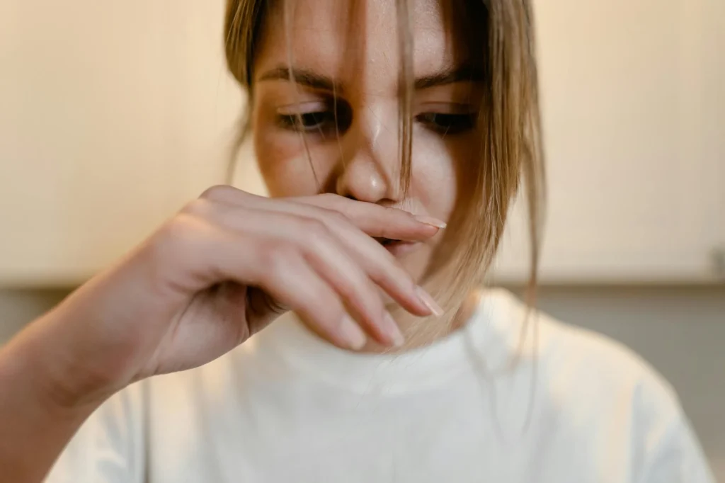 A person in a white shirt gazes downward, hand near their mouth, seemingly pondering what to do when you feel lost.